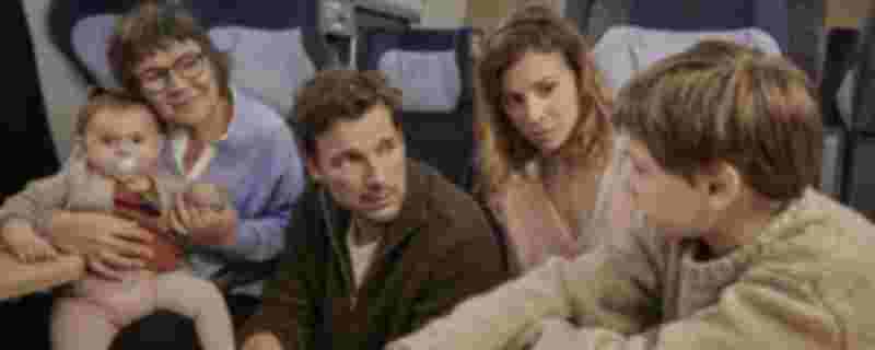 Ein Baby auf dem Arm einer älteren Frau, ein Mann, eine weitere Frau und ein Kind sitzen in einem Zug Ein Baby auf dem Arm einer älteren Frau, ein Mann, eine weitere Frau und ein Kind sitzen in einem Zug